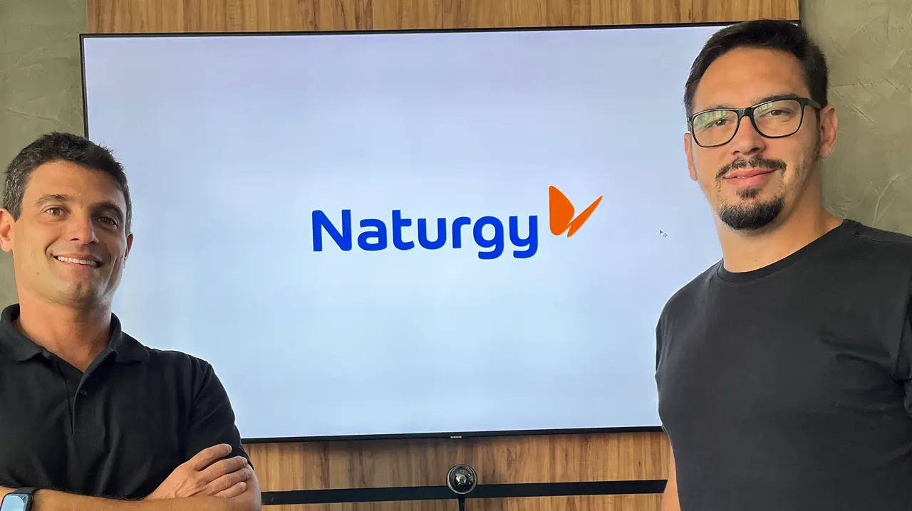 Sócios da SIDES ao lado de uma televisão com a logotipo da Naturgy na tela.